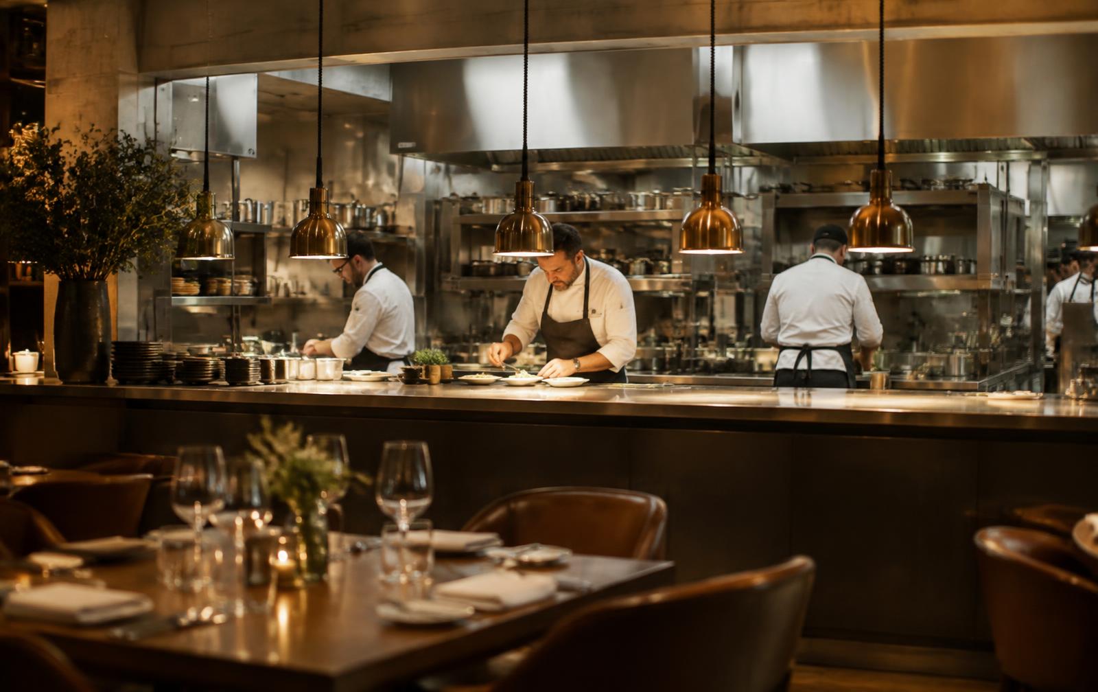 Restaurant dining room looking into an open kitchen during service